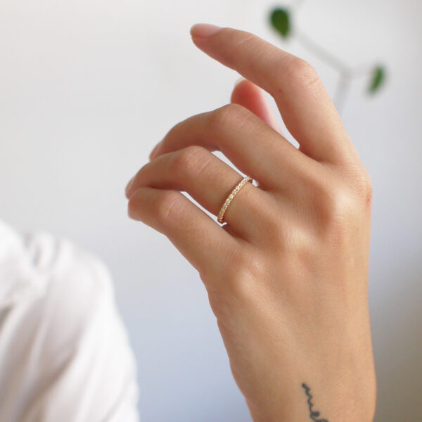 Mulher usando Aliança de 1,5mm cravejada de diamantes minimalista feita a mão em ouro 18k para casamentos