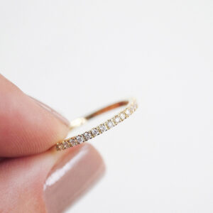 Mulher segurando Aliança slim cravejada de diamantes minimalista feita a mão em ouro 18k para casamentos