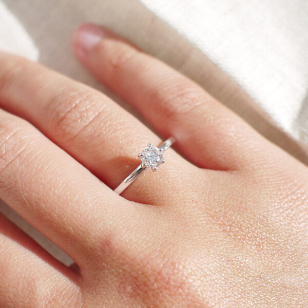Mulher usando anel solitário minimalista com diamantes de 40p em ouro 18k