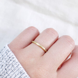 Aliança de aro redondo 1,8mm com diamantes minimalista feita a mão em ouro 18k para casamentos sobre fundo branco