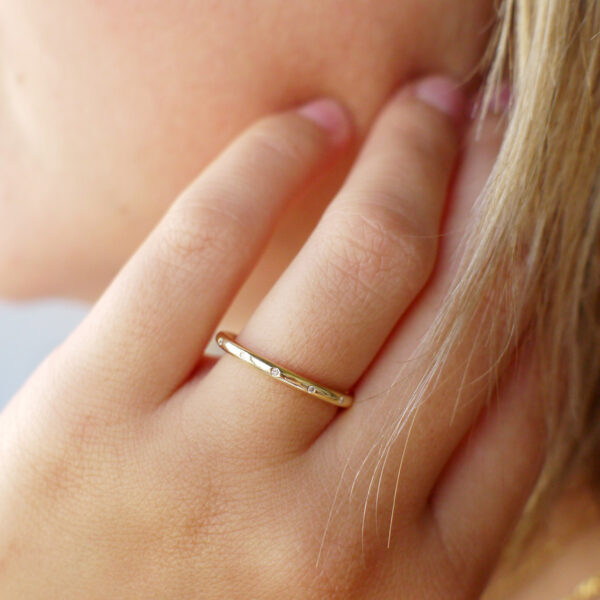 Mulher usando Aliança de aro redondo 1,8mm com diamantes minimalista feita a mão em ouro 18k para casamentos