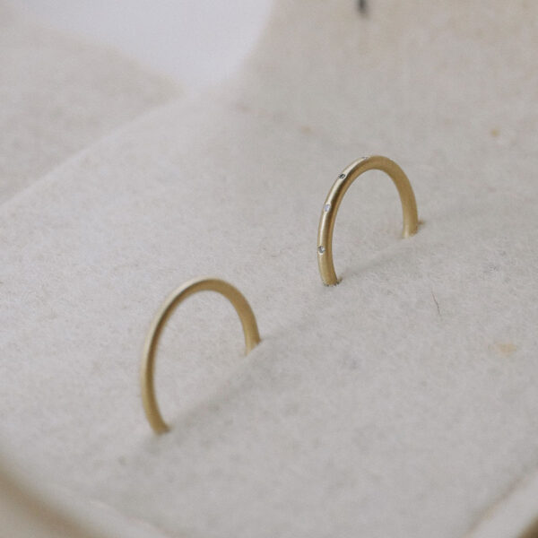 Par de alianças de aro redondo 1,8mm com diamantes minimalistas feitas a mão em ouro 18k para casamentos sobre embalagem de feltro
