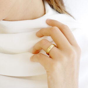 Mulher de tricot usando Aliança de casamento feita a mão em ouro 18k arredondada minimalista