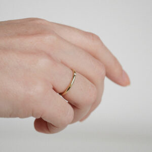 Mão feminina usando aliança de 2mm minimalista feita a mão em ouro 18k com diamantes para casamentos