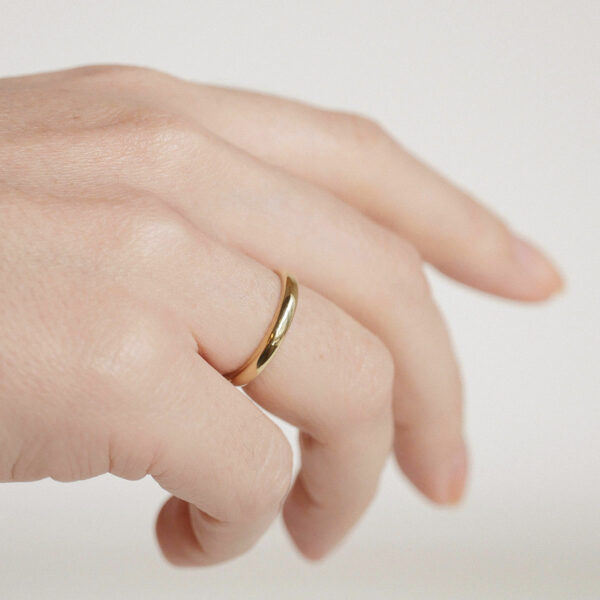 Mão feminina usando aliança de 3mm minimalista feita a mão em ouro 18k com diamantes para casamentos