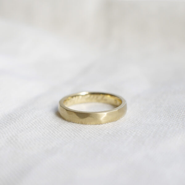 Aliança de casamento feita a mão em ouro 18k facetada minimalista sobre tecido branco