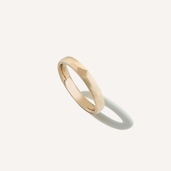 Aliança de casamento feita a mão em ouro 18k facetada minimalista sobre fundo branco