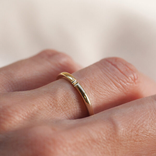 mão feminina com aliança de casamento feita à mão em ouro 18k que o par forma um coração minimalista