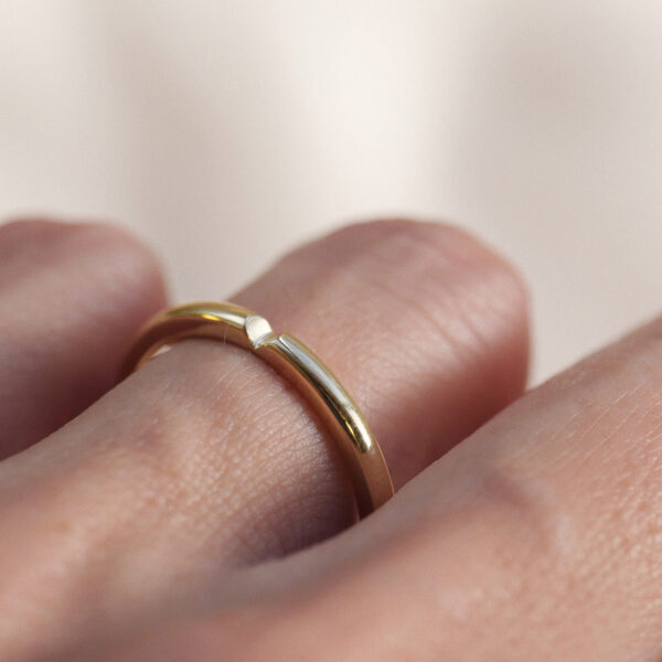 mão feminina com aliança de casamento feita à mão em ouro 18k que o par forma um coração minimalista