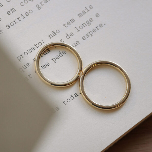 par alianças de casamento feita à mão em ouro 18k que o par forma um coração minimalista sobre livro