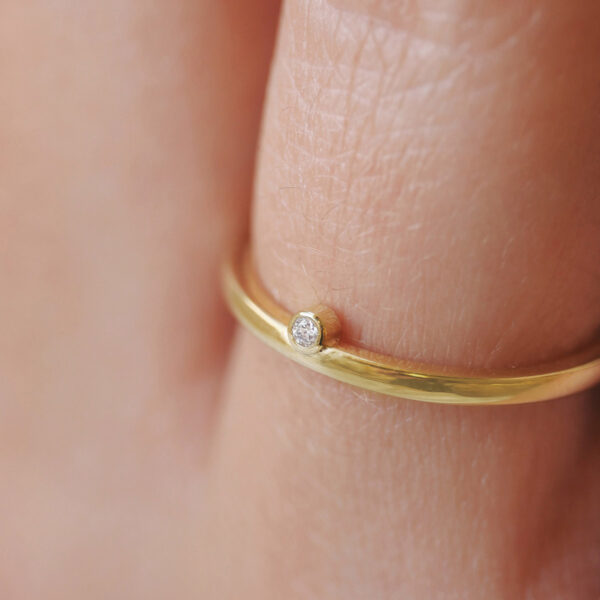 Mulher usando aliança minimalista feita a mão em ouro 18k com encaixe de diamante para casamentos