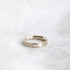 aliança de casamento feita à mão em ouro 18k e diamante central minimalista sobre tecido