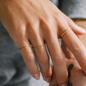 Mão feminina usando Aliança de aro redondo 1,8mm minimalista feita a mão em ouro 18k para casamentos e anéis com diamantes