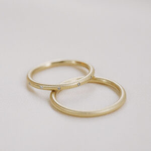Par de alianças de aro redondo 1,8mm minimalistas feitas a mão em ouro 18k para casamentos sobre fundo branco