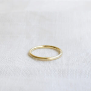 Aliança de aro redondo 1,8mm minimalista feita a mão em ouro 18k para casamentos sobre tecido branco