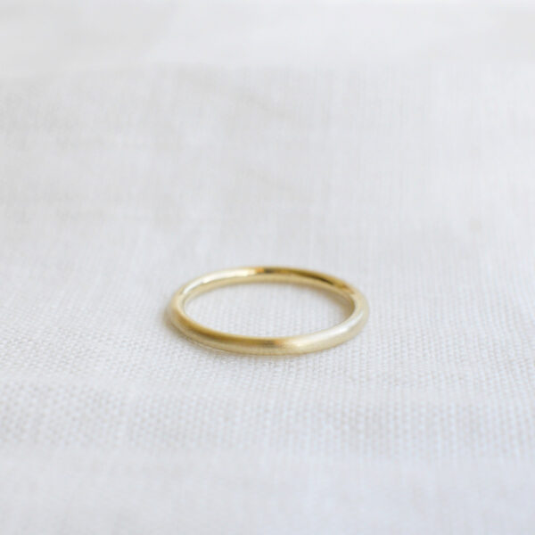 Aliança de aro redondo 1,8mm minimalista feita a mão em ouro 18k para casamentos sobre tecido branco