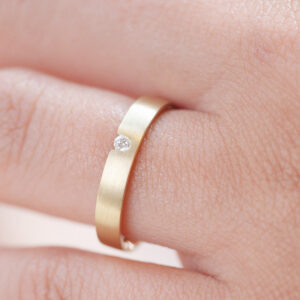 mão feminina com aliança de casamento feita a mão em ouro 18k e diamante central de 3 pontos minimalista