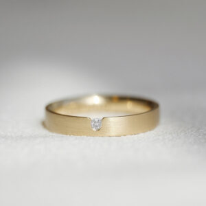 aliança de casamento feita à mão em ouro 18k e diamante central de 3 pontos minimalista sobre fundo branco