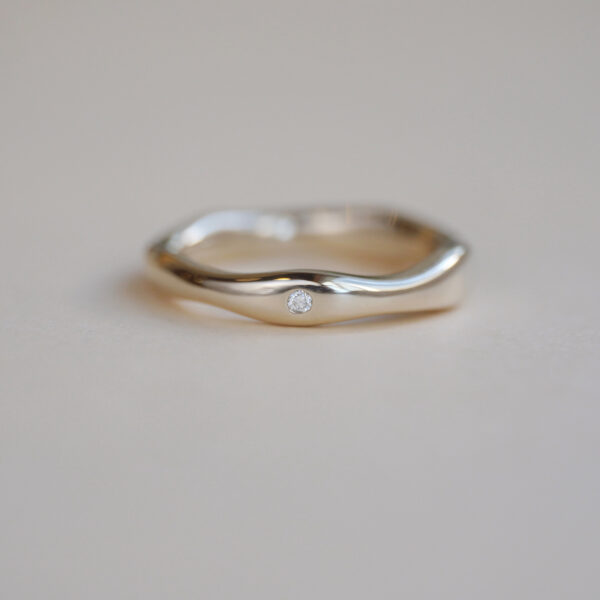 Aliança irregular orgânica minimalista feita a mão em ouro 18k para casamentos sobre fundo branco