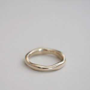 Aliança irregular orgânica minimalista feita a mão em ouro 18k para casamentos sobre fundo branco