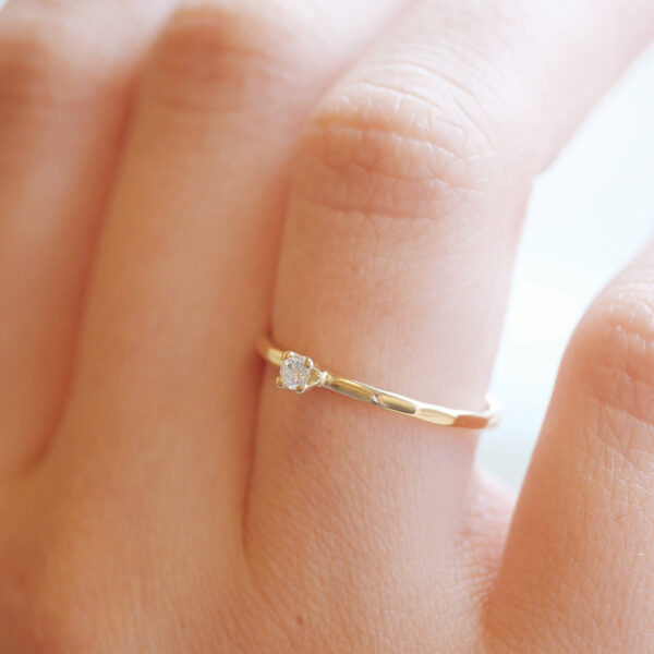 Mão feminina usando Anel solitário minimalista martelado para noivado em ouro 18k com diamante