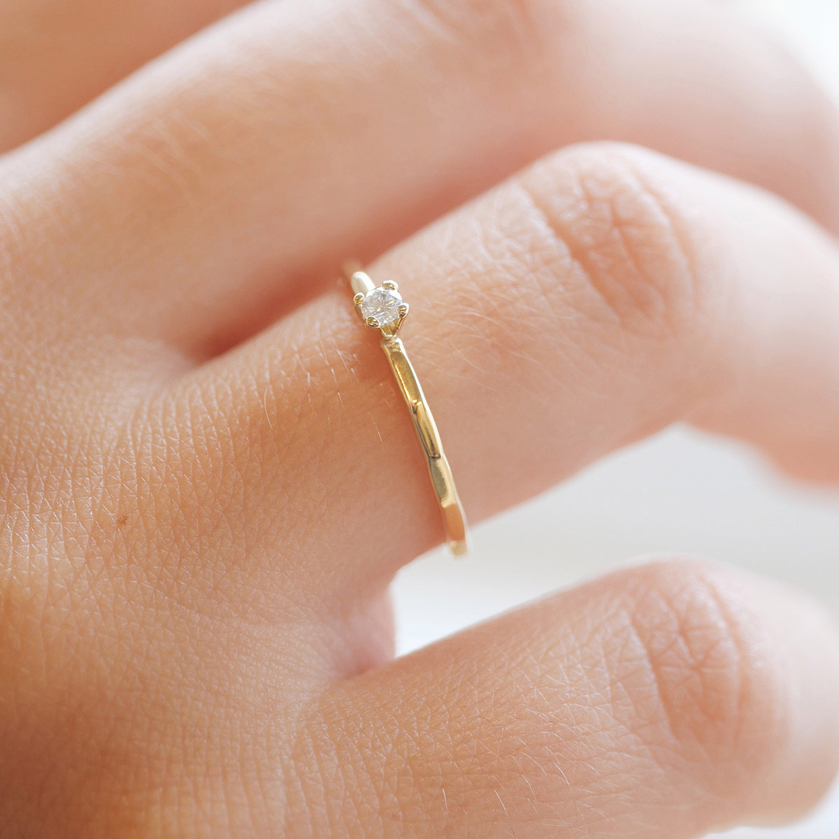 Mão feminina usando Anel solitário minimalista martelado para noivado em ouro 18k com diamante
