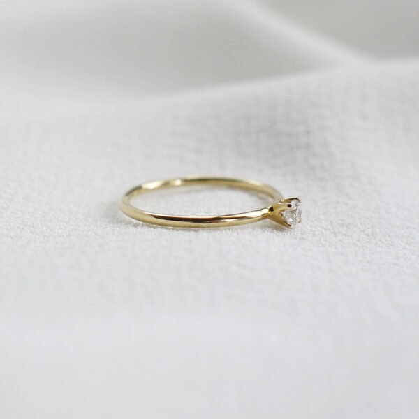 Anel de noivado minimalista feito a mão em ouro 18k com diamante sobre tecido branco