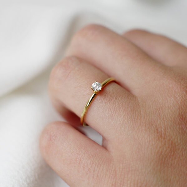 Mão feminina usando Anel de noivado minimalista feito a mão em ouro 18k com diamante