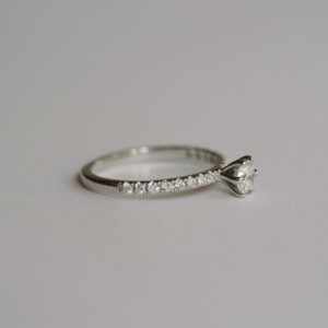Anel solitário cravejado minimalista de diamantes em ouro 18k sobre fundo branco
