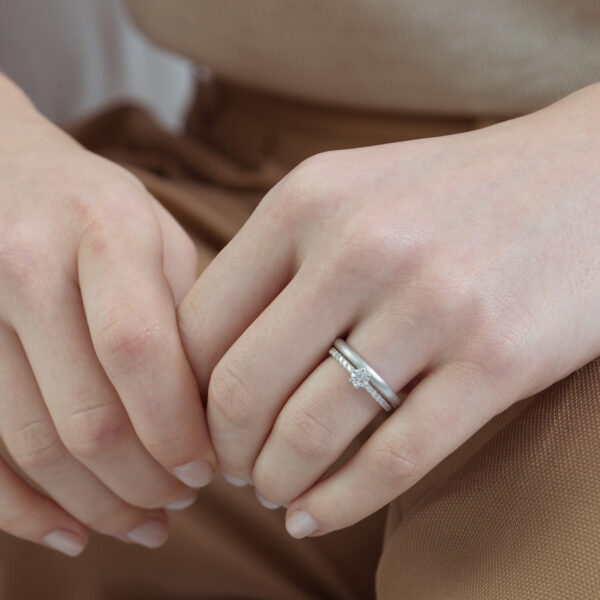 Mão feminina usando anel solitário cravejado minimalista de diamantes em ouro 18k
