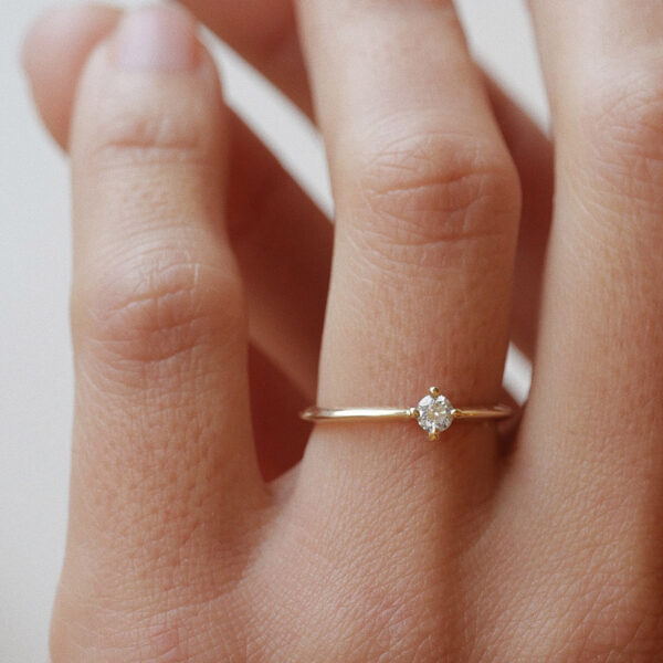 Mulher usando anel solitário minimalista com diamantes de 13p em ouro 18k