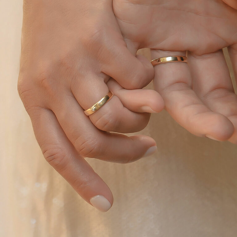 Mãos entrelaçadas usando Par de alianças minimalistas feitas a mão em ouro 18k com diamante para casamentos