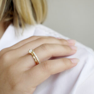 Mulher de blusa branca usando Aliança cravejada minimalista feita a mão em ouro 18k para casamentos sobre fundo branco