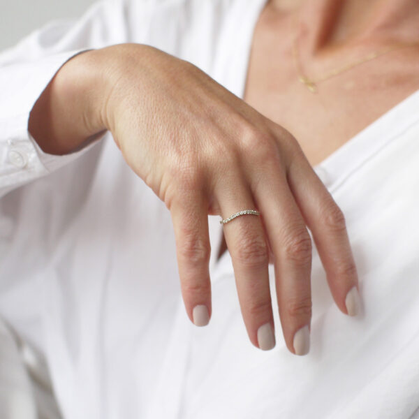 Mulher usando aliança cravejada minimalista feita a mão em ouro 18k para casamentos
