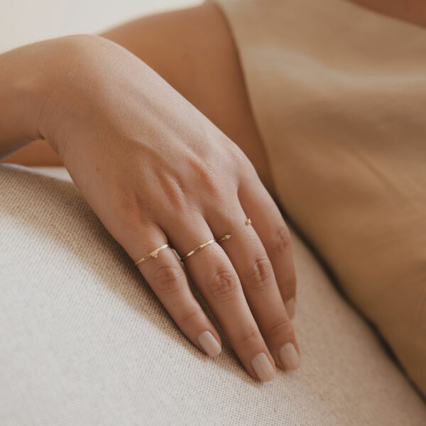 Mão feminina com anéis e aliança martelada minimalista feita a mão em ouro 18k