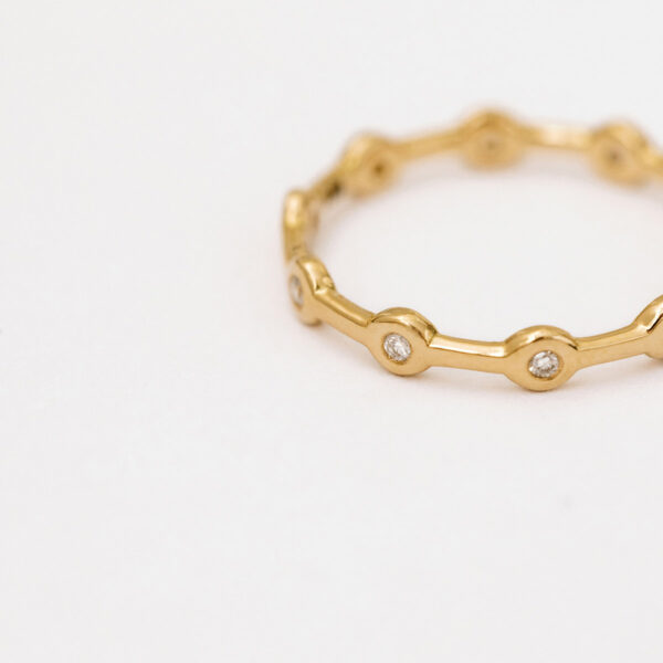 Aliança minimalista em ouro 18k feita a mão com diamantes sobre fundo branco para casamentos