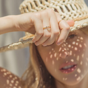 Mulher de chapéu usando Anéis minimalistas feitos a mão em ouro 18k com curvas e diamantes