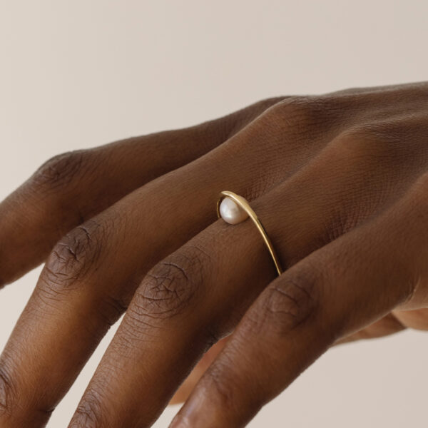 Mulher usando Anel minimalista de formato oval com pérola natural feito a mão em ouro 18k