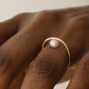 Mulher usando Anel minimalista de formato oval com pérola natural feito a mão em ouro 18k