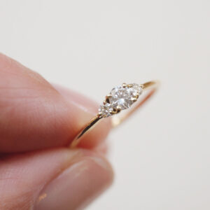 Mão feminina segurando Anel de noivado em ouro 18k com diamante de 18p minimalista feito a mão
