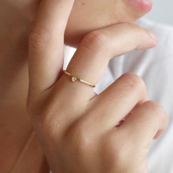 Mão feminina usando anel martelado em ouro 18k com diamante minimalista para noivado