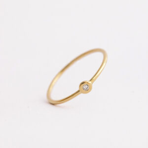 Anel de aro fino minimalista feito a mão em ouro 18k com diamante sobre fundo branco