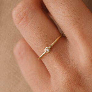Mão vestindo Anel de aro fino minimalista feito a mão em ouro 18k com diamante