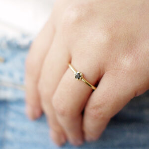 mão feminina usando anel solitário de noivado minimalista de ouro 18k com diamante negro feito à mão