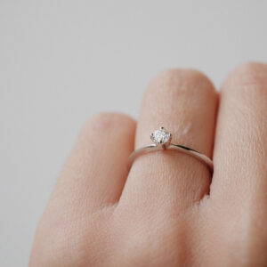 Mão feminina usando Anel Solitário minimalista para noivado com diamante em ouro 18k