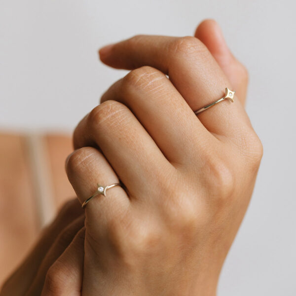 Mão vestindo Anéis minimalistas feitos a mão em ouro 18k com estrela e diamante no centro