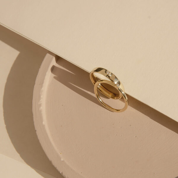 anel de noivado e aliança de casamento em ouro 18k e diamantes minimalistas e feitos à mão sobre mesa