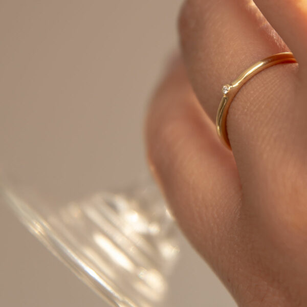 mão feminina usando anel de noivado minimalista de ouro 18k com diamante de 1p feito à mão