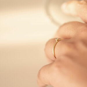 mão feminina usando anel de noivado minimalista de ouro 18k com diamante de 5p feito à mão