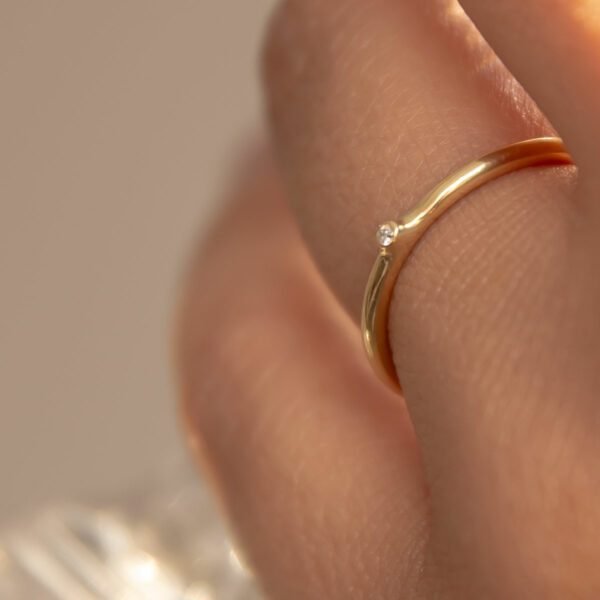 mão feminina usando anel de noivado minimalista de ouro 18k com diamante de 1p feito à mão